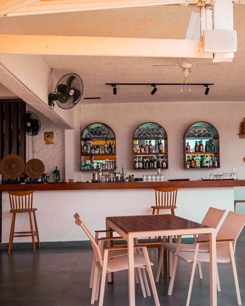 A whitewashed bar in Türkbükü, bottles lit in three arched niches above wooden stools