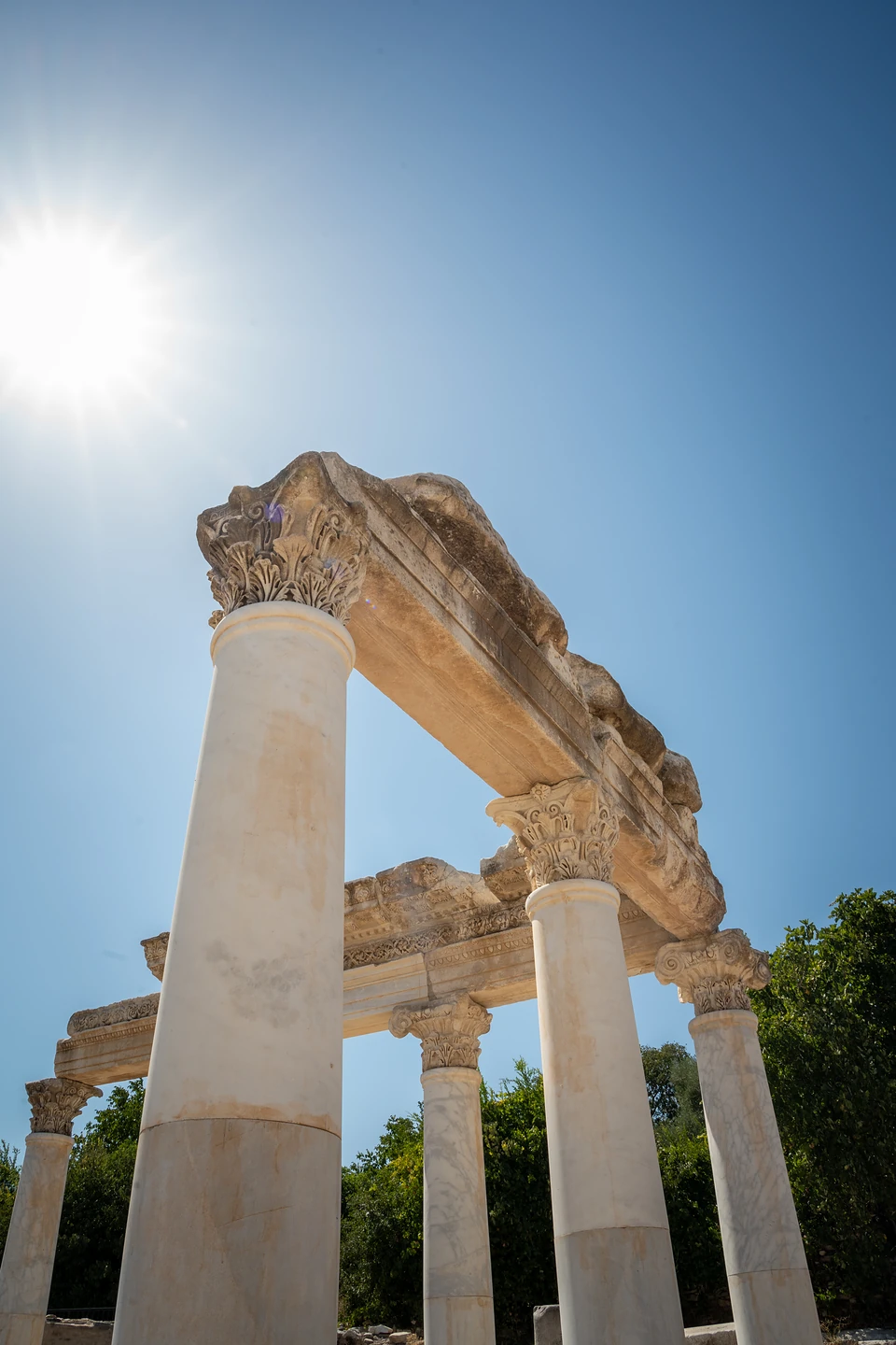 Looking up at marble columns and their carved lintels, the sun blazing in a clear sky