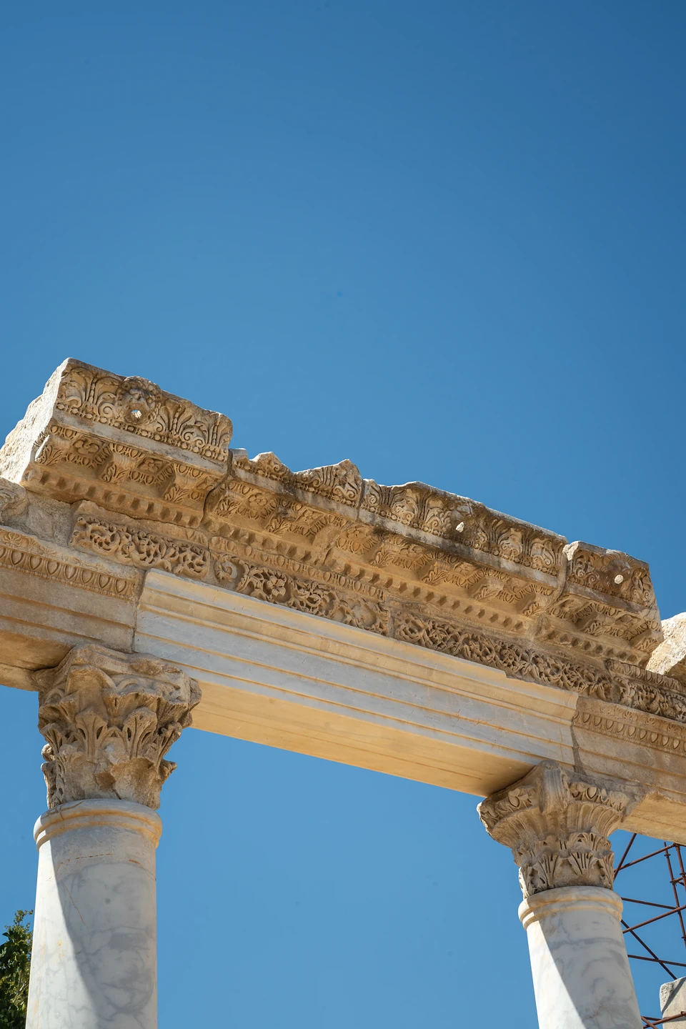 A richly carved stone lintel resting on two leafy capitals against deep blue sky