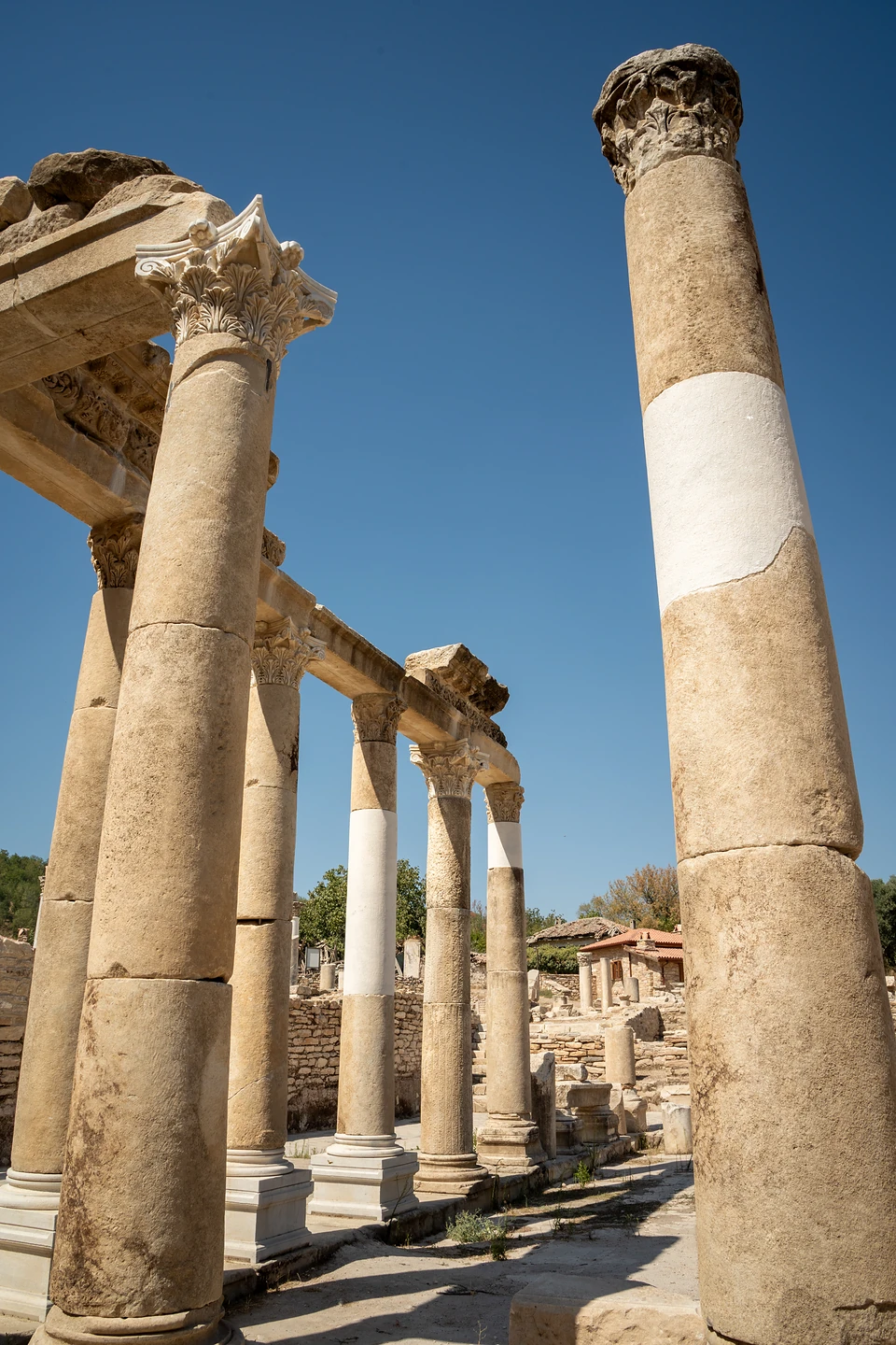 Tall columns patched with bands of bright white stone, seen from below along a colonnade