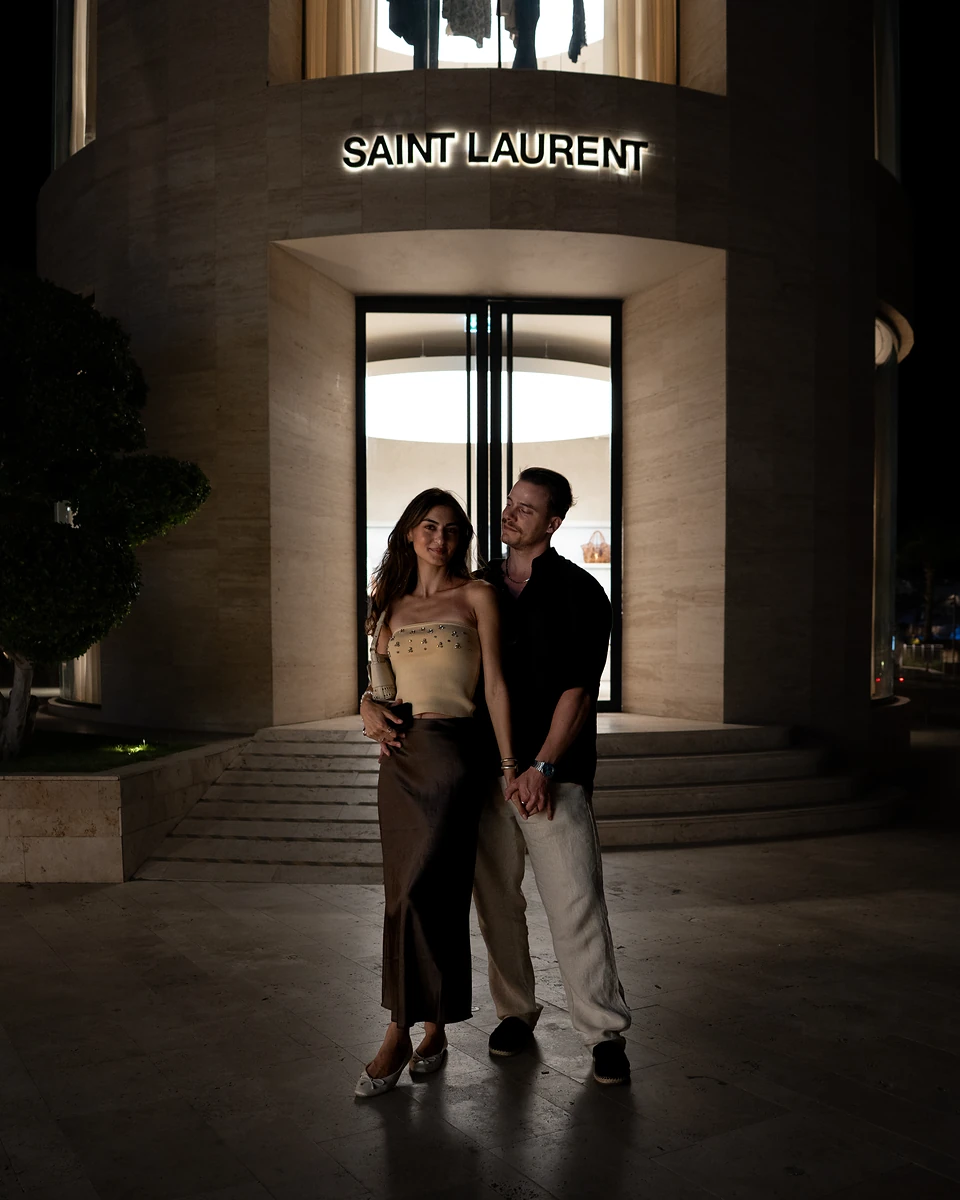 The two of us at night under a lit shop sign in Yalıkavak