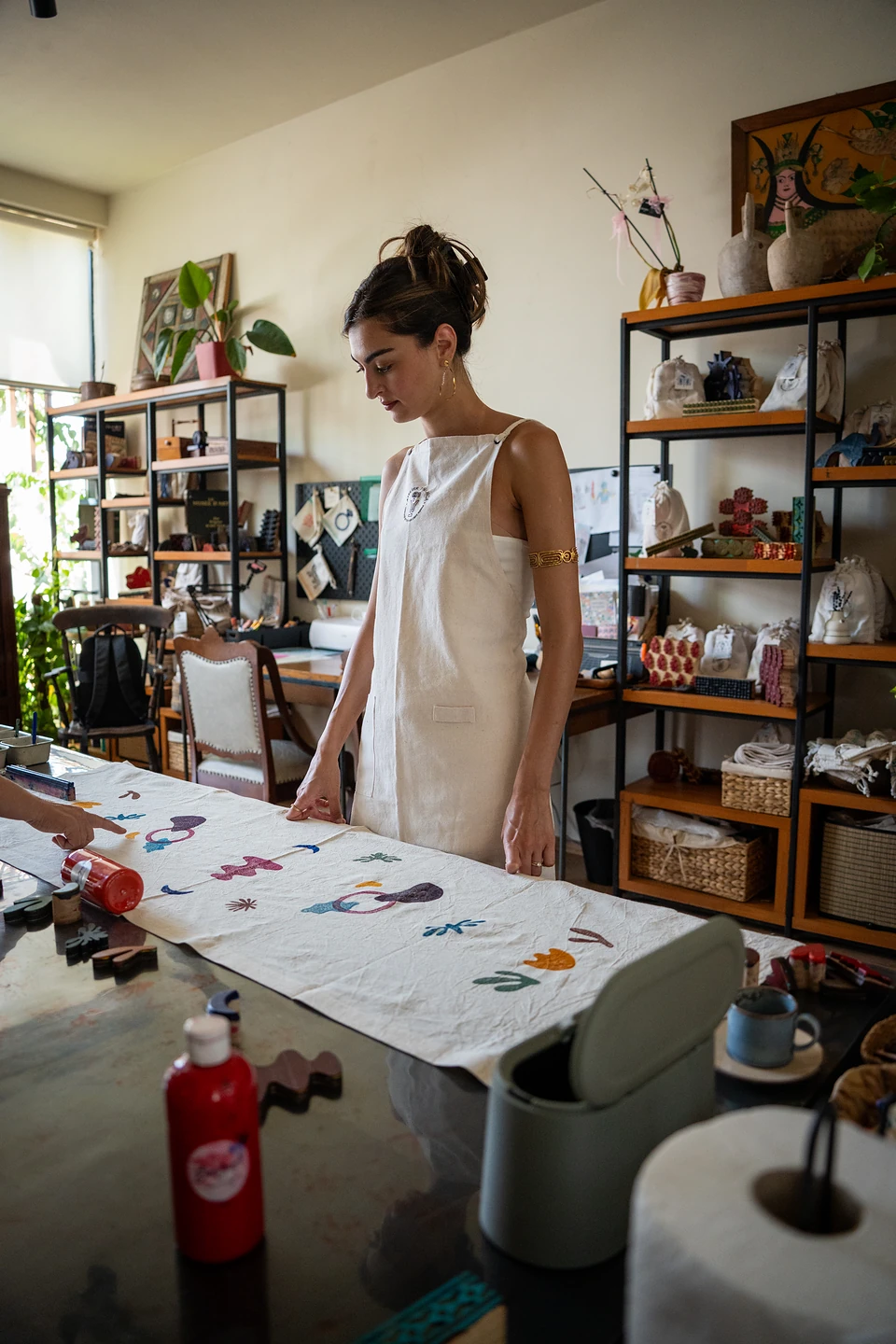 One of us standing over a cloth of scattered printed shapes, shelves of goods behind