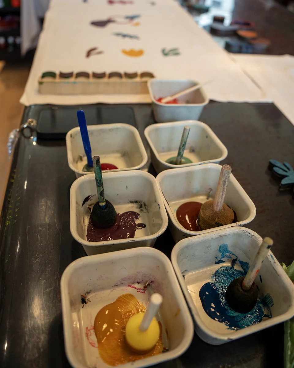 Tubs of paint in burgundy, rust, blue and yellow, each with its own sponge dauber