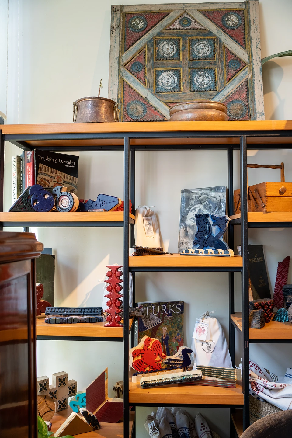 Shelves of books and colourful carved printing blocks beneath an old painted wooden panel