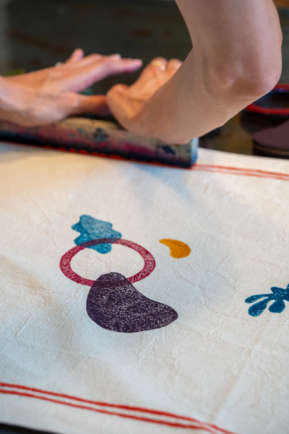 One of us pressing a long block beside a freshly printed red ring and purple shape