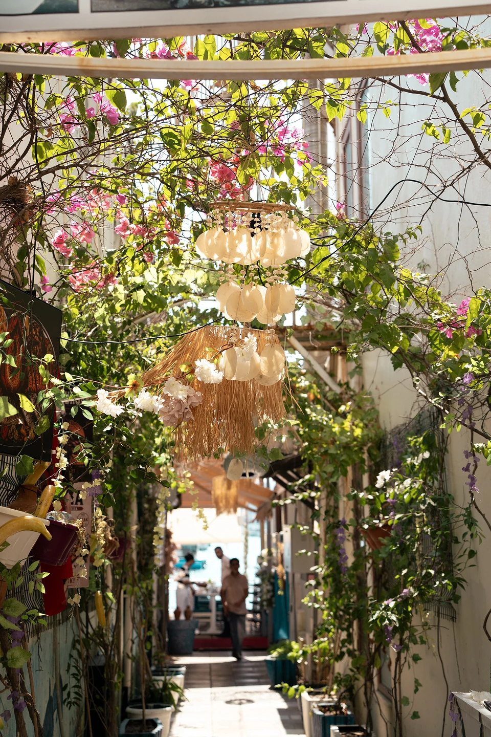 A narrow Bodrum lane hung with pale ornaments and raffia, people walking at the far end