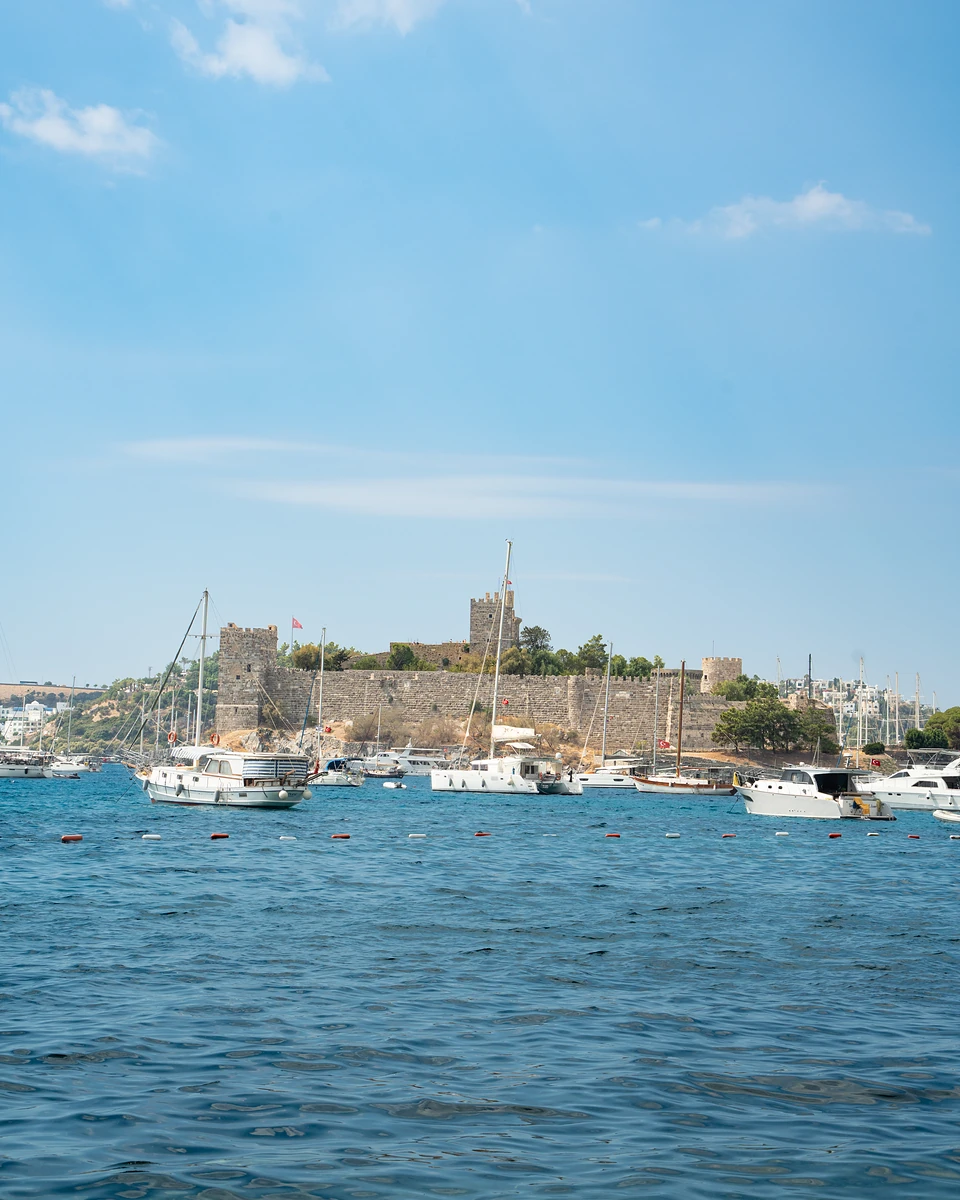 Yachts and gulets moored in Bodrum harbour below the stone walls and towers of the castle