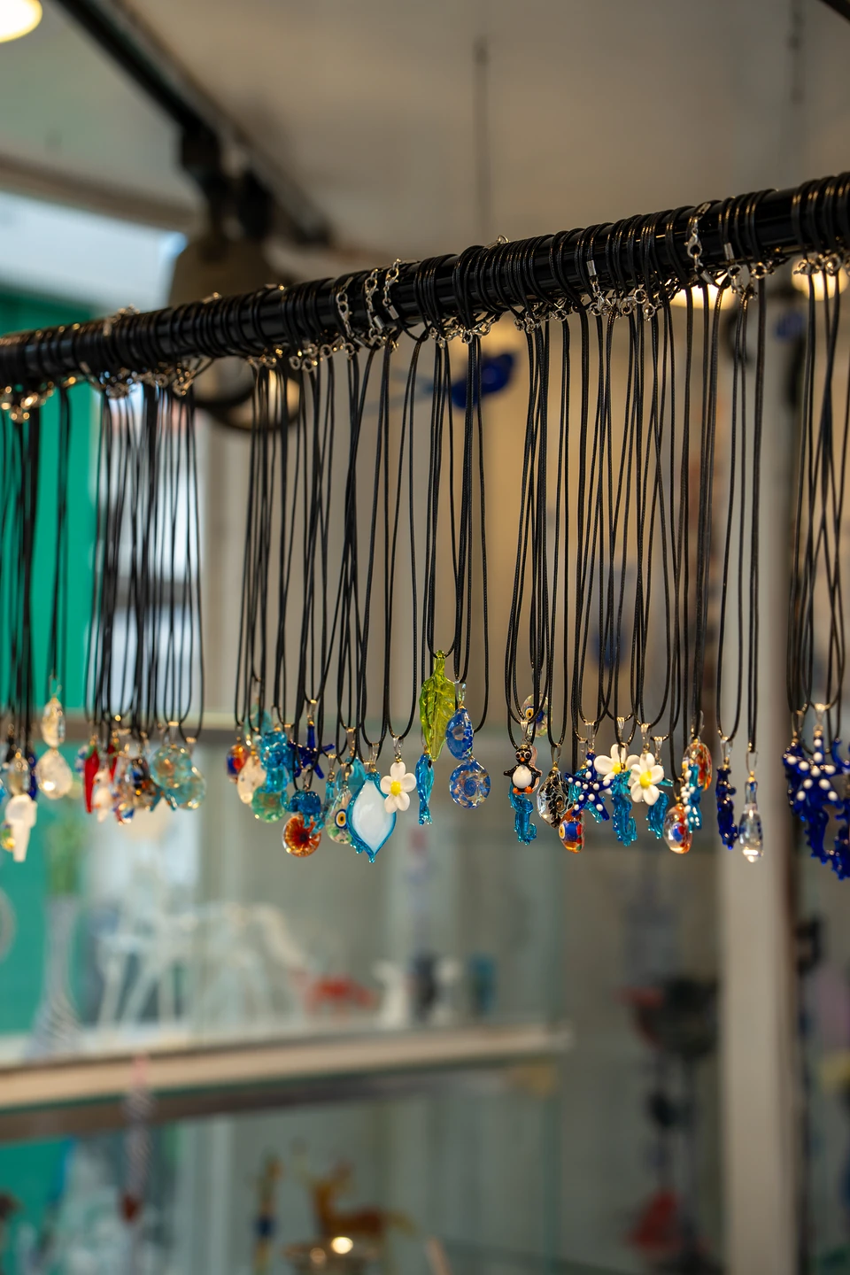 Blue glass pendants shaped like flowers, starfish and drops on black cords in a Bodrum shop