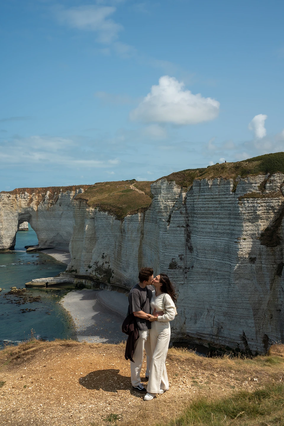 The two of us kissing on the clifftop, white chalk cliffs and an arch behind