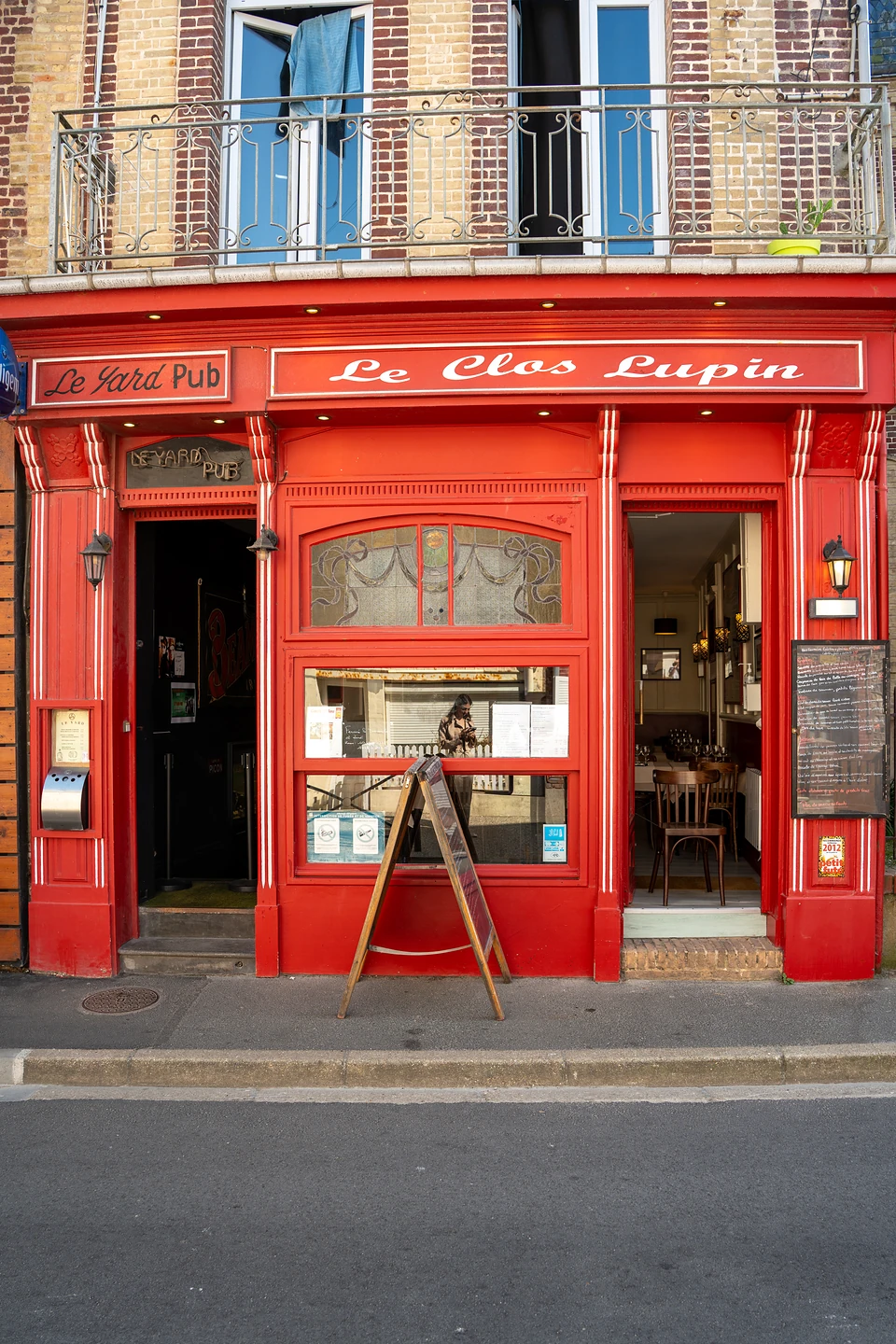 The red painted shopfront of Le Clos Lupin, a sandwich board on the pavement