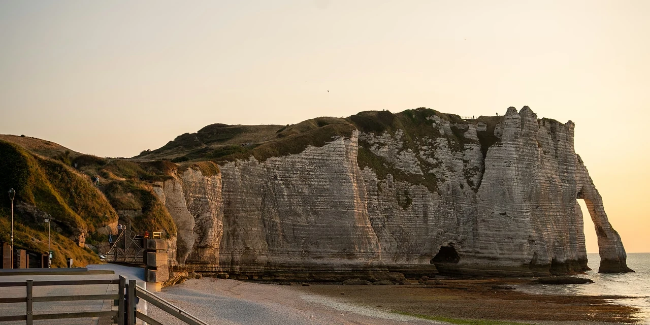 Two small boats drawn up on the shingle, the chalk arch behind in sunset light