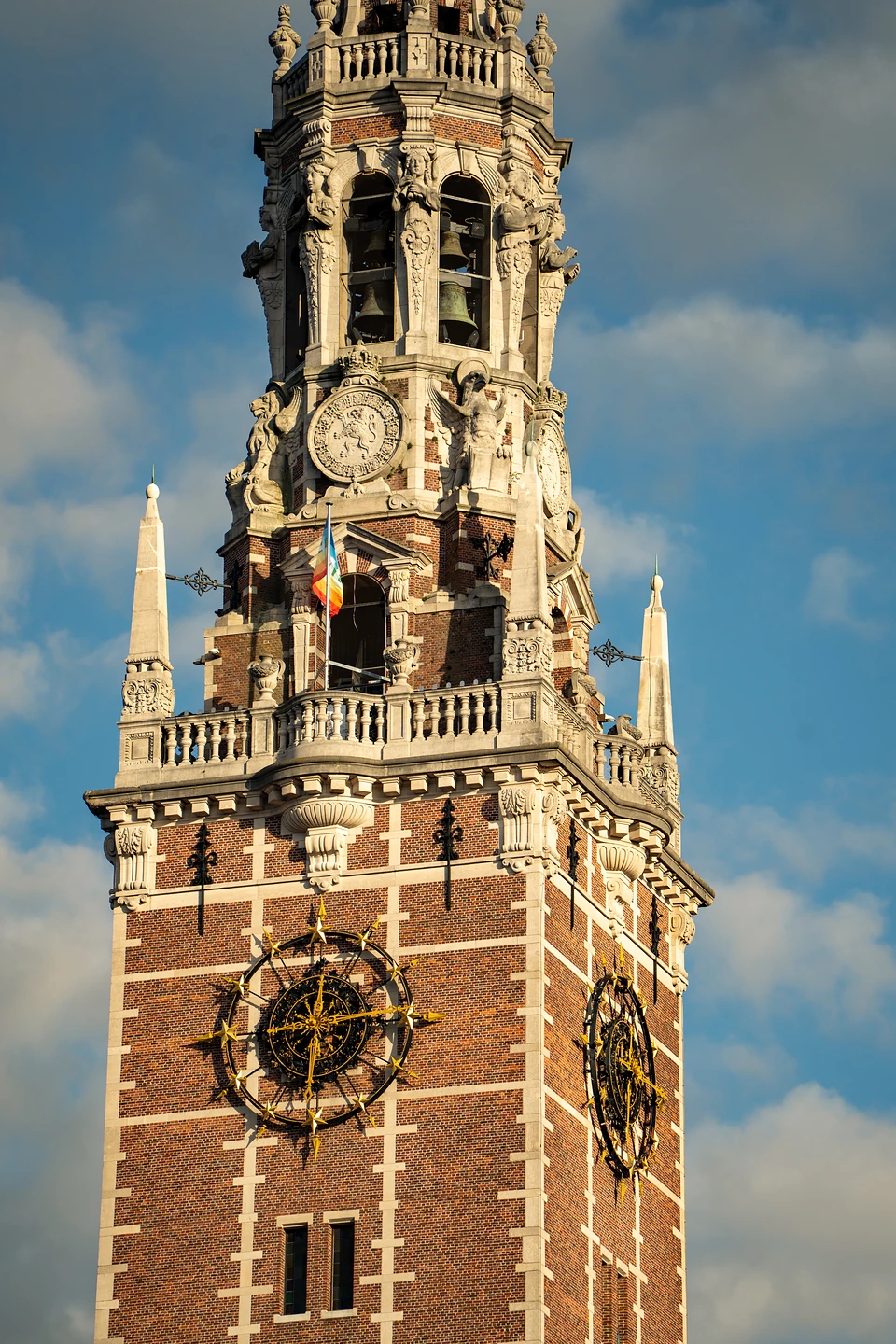 The library tower’s bells, gilded clock and a small rainbow flag in golden evening light