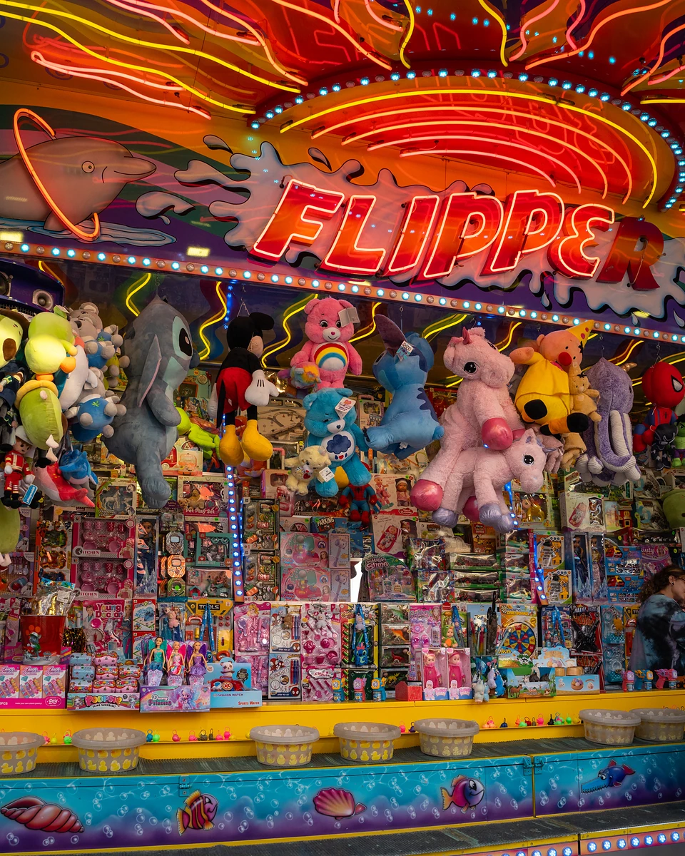 Neon ‘Flipper’ lettering glowing over shelves of boxed toys and cartoon plush prizes