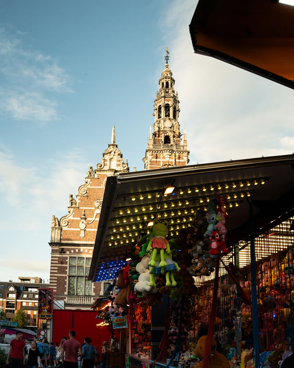 The library tower and an ornate gable behind a lit prize stall hung with plush toys