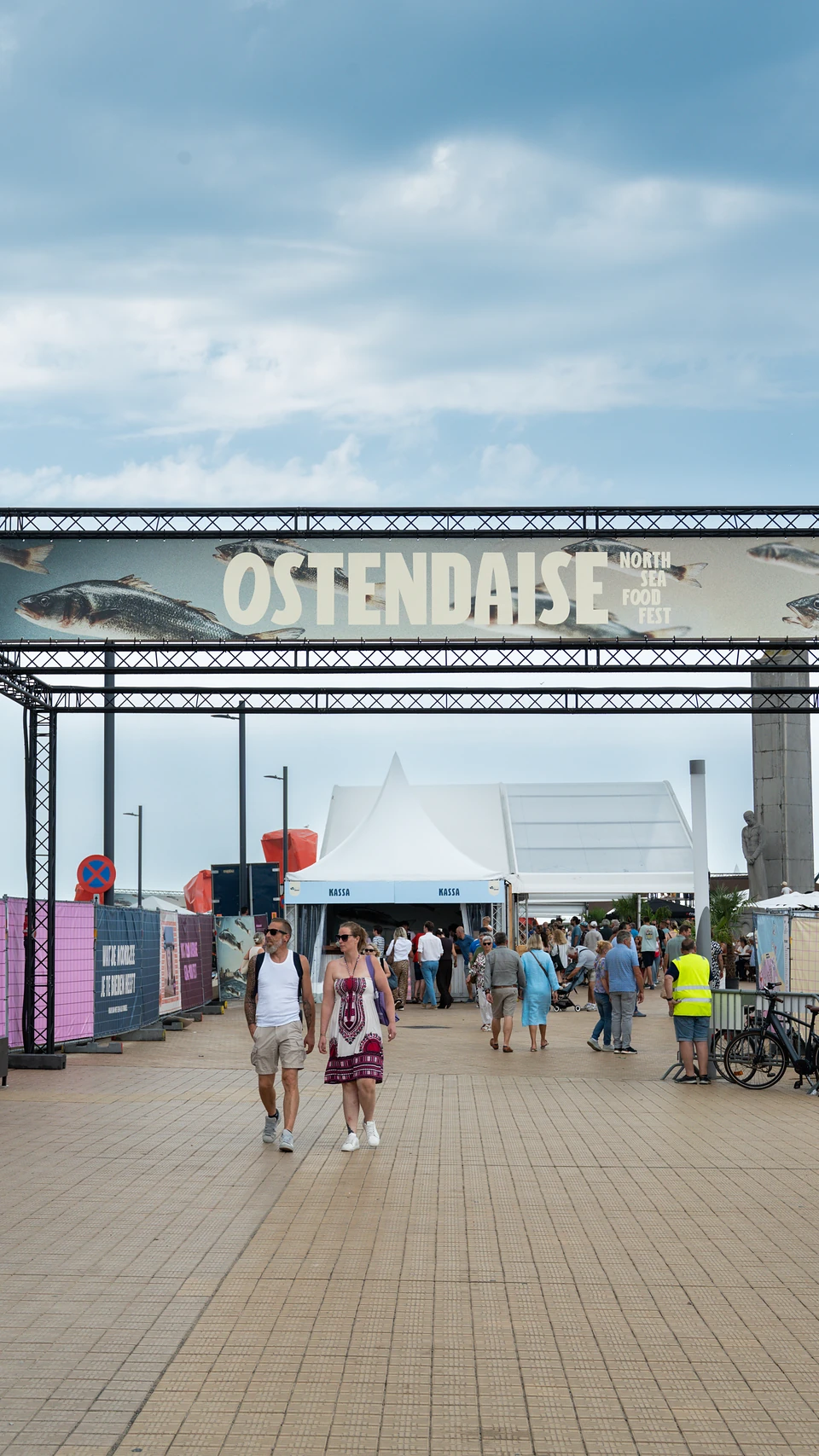 Visitors walking beneath the 'Ostendaise North Sea Food Fest' arch, white tents behind