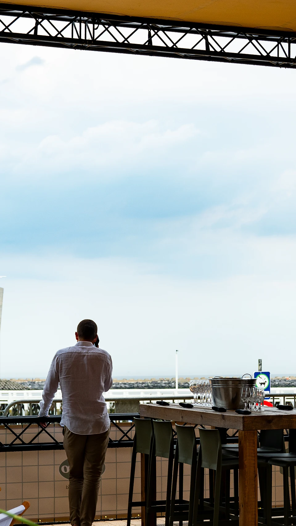 A man in a white shirt looking out to sea from a festival terrace