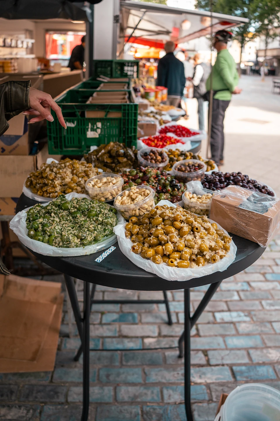 Platters of marinated olives and tubs of nuts heaped on a table at the Saturday market