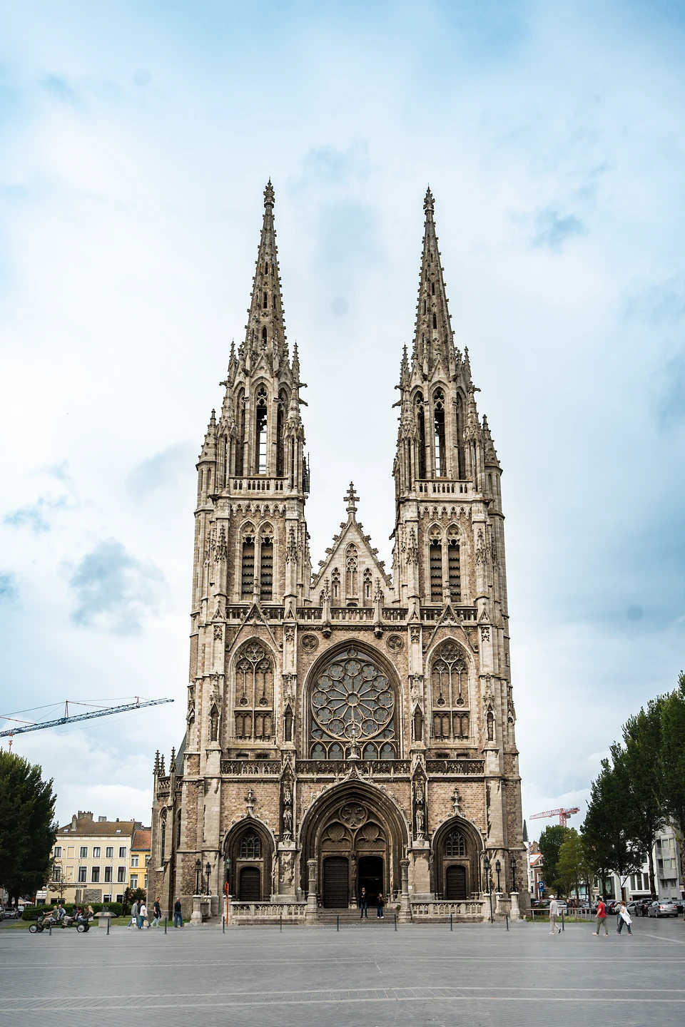 A twin-spired Gothic-style church front with its rose window, seen across an open square