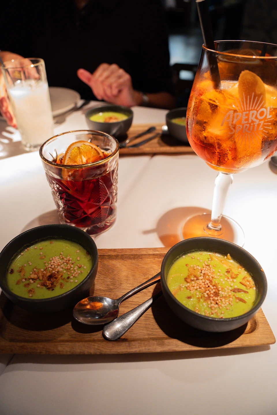 Two bowls of green soup and an Aperol Spritz, one of us across the table