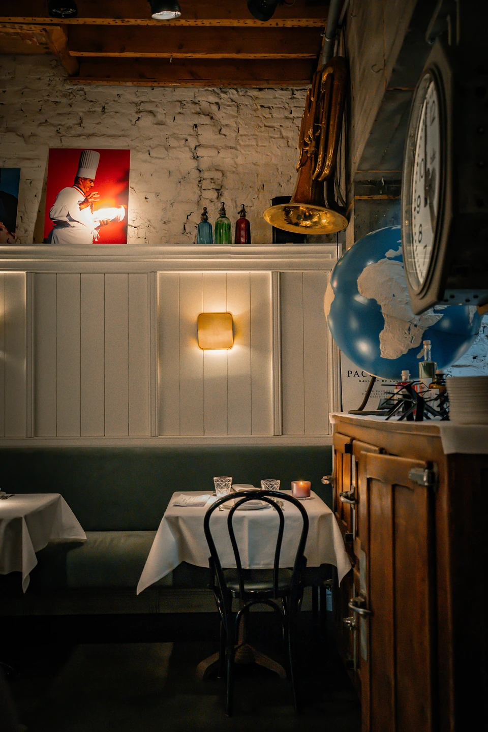 A single table laid in white by a globe, a wall clock and a brass horn