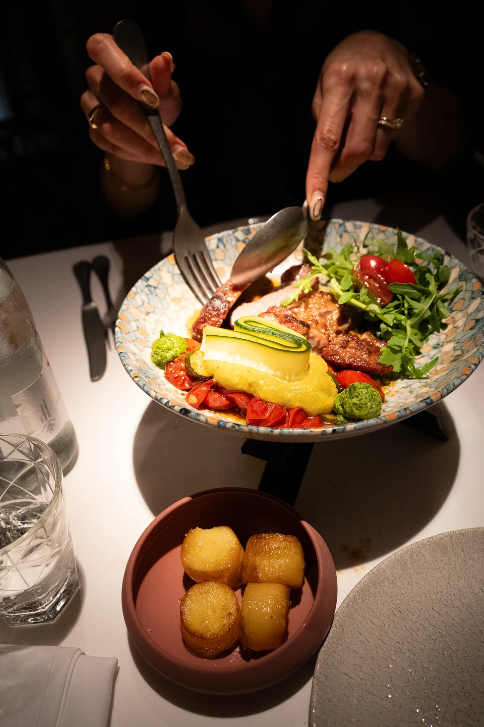 One of us serving from the mosaic bowl, a side of four golden potatoes in front